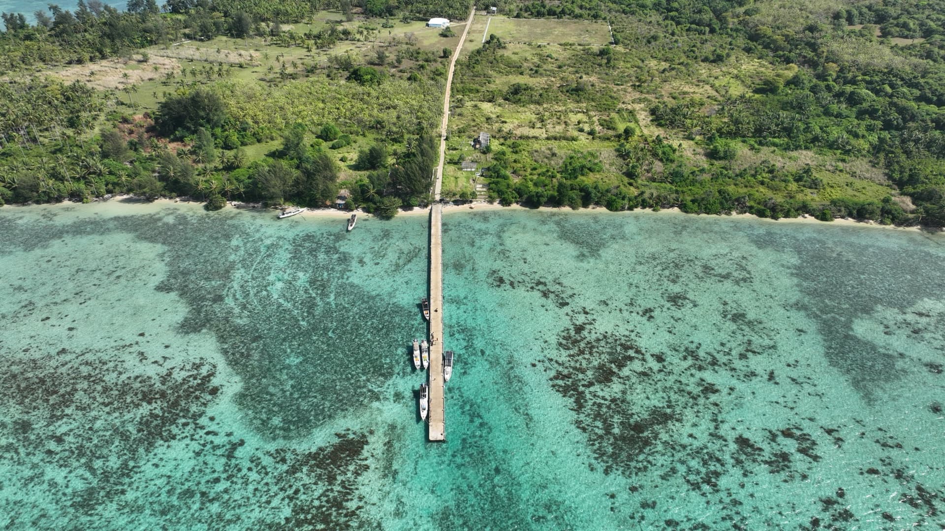 Dermaga panjang Pulau Parang membelah hamparan terumbu karang dangkal.